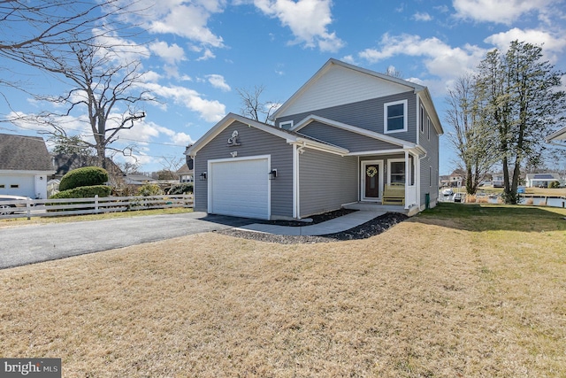 view of front of house with a front yard, an attached garage, driveway, and fence