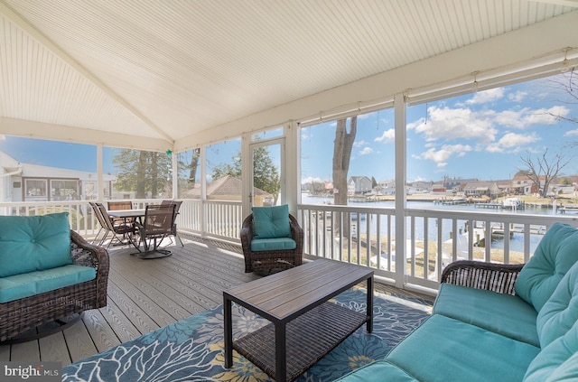 sunroom featuring vaulted ceiling and a water view