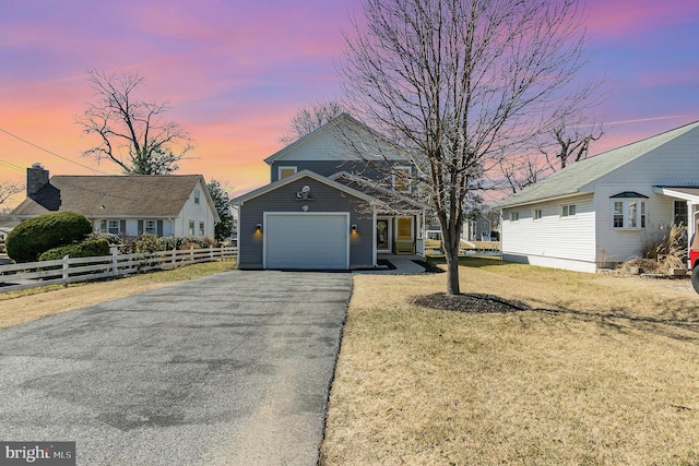 view of front facade with driveway, an attached garage, a yard, and fence