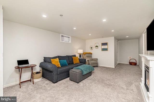 living area with a glass covered fireplace, recessed lighting, light colored carpet, and baseboards