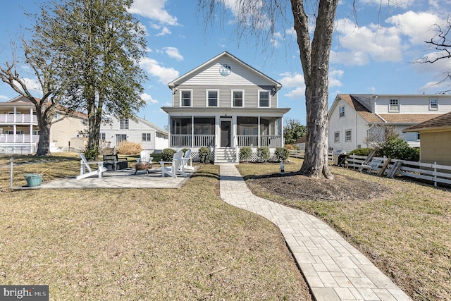 view of front of home featuring a patio, fence, a fire pit, a front yard, and a sunroom