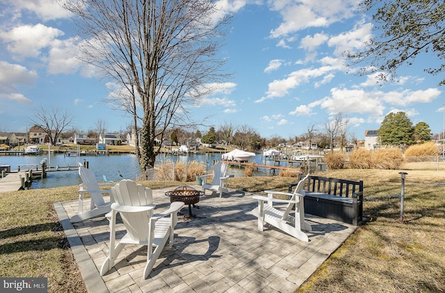 view of patio / terrace with boat lift, a fire pit, a dock, and a water view