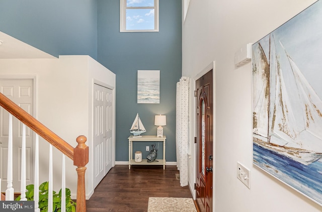 foyer entrance with stairs, a high ceiling, wood finished floors, and baseboards