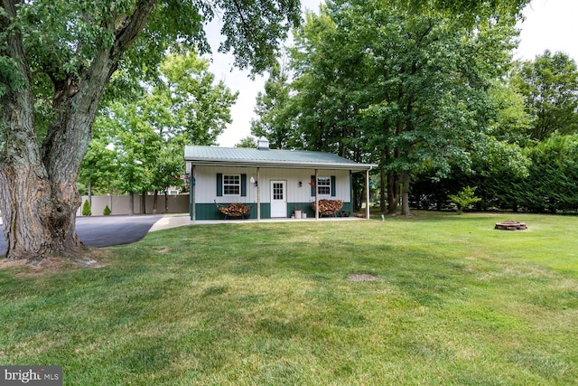 single story home with metal roof, a porch, a front yard, and fence