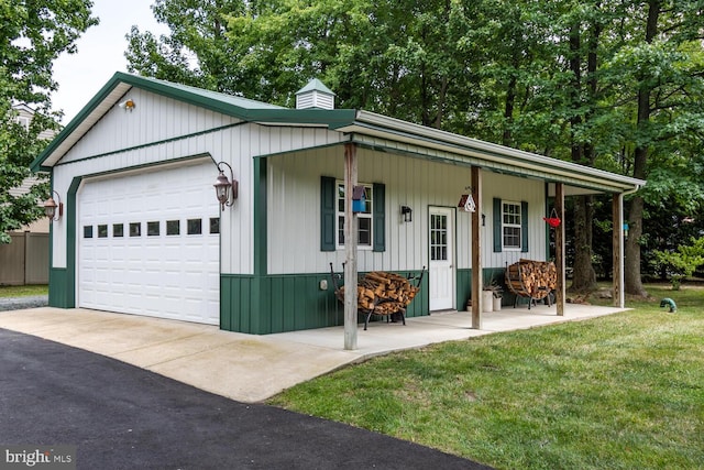 single story home featuring a chimney, a porch, a front lawn, and a detached garage