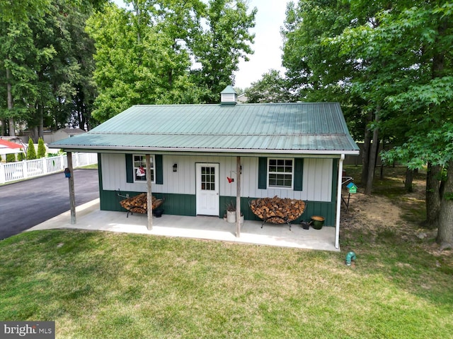 view of front of house featuring fence, metal roof, board and batten siding, and a front yard