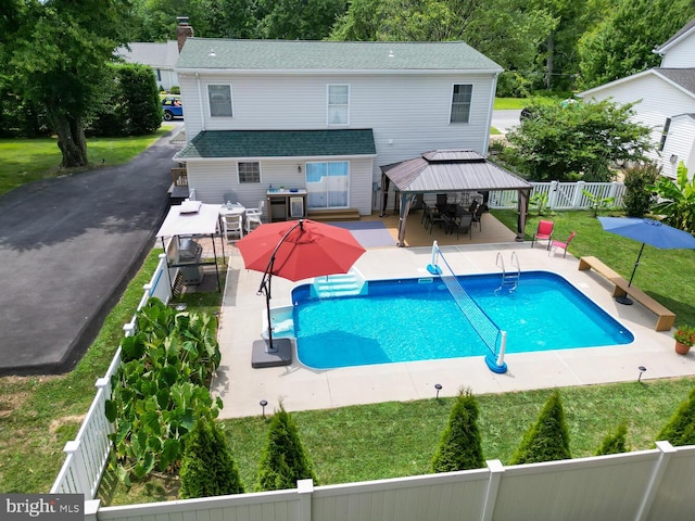 back of house featuring a lawn, a gazebo, a patio area, a fenced backyard, and an outdoor pool