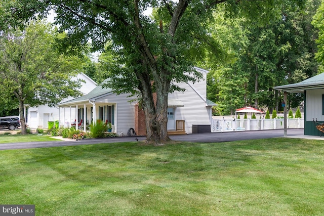 view of side of home with a porch, fence, and a lawn