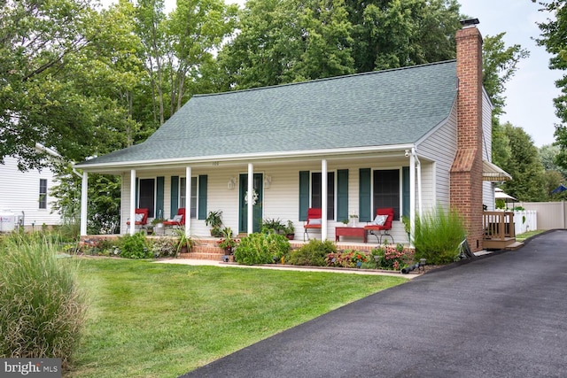 view of front of house with a chimney, a front lawn, a porch, and roof with shingles