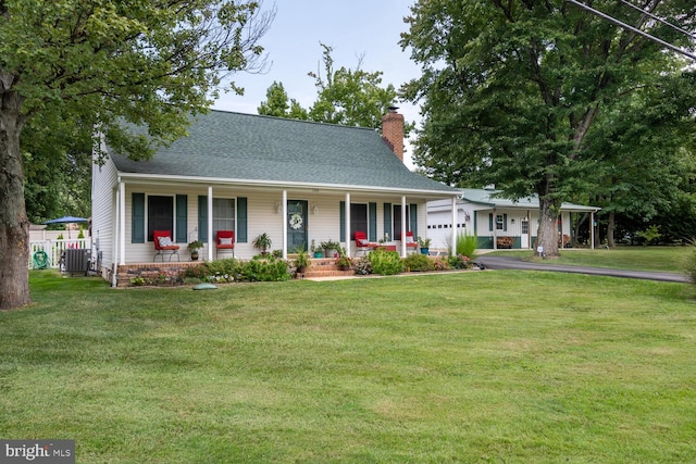 view of front facade with a garage, a chimney, covered porch, a front lawn, and central AC