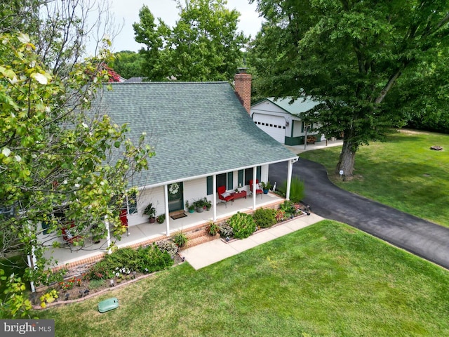 view of front of home featuring a porch, aphalt driveway, a shingled roof, a front lawn, and a chimney