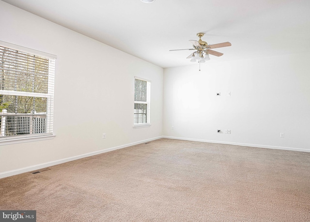 empty room featuring visible vents, light carpet, baseboards, and a ceiling fan