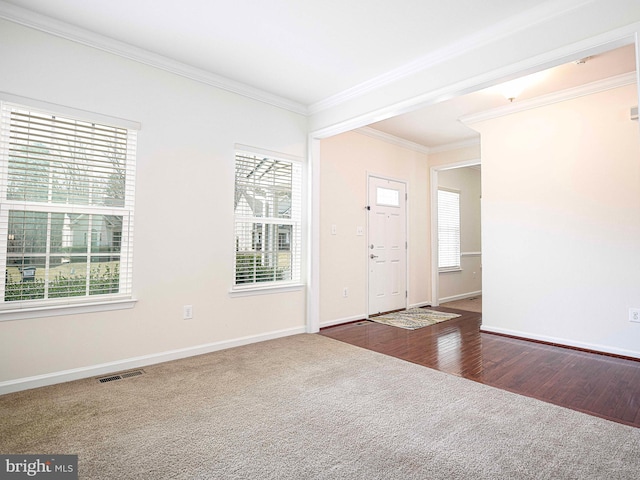 foyer with a wealth of natural light, visible vents, dark wood-style flooring, and ornamental molding