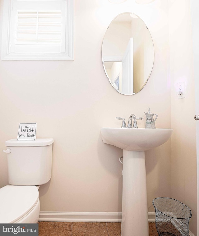 half bathroom with tile patterned floors, toilet, and baseboards