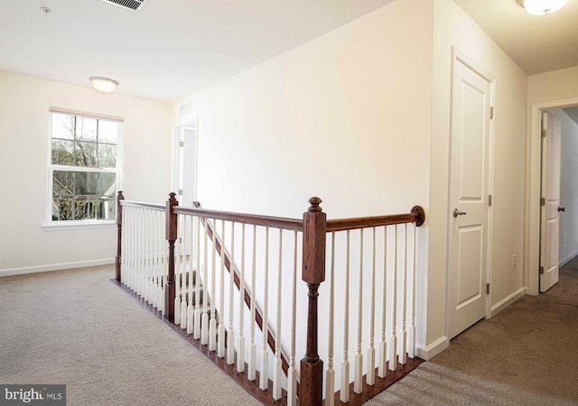 hallway with baseboards, carpet, and an upstairs landing