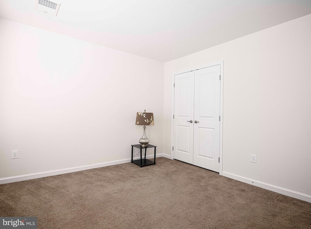 carpeted spare room featuring visible vents and baseboards