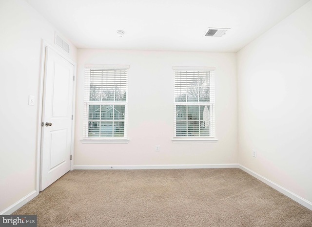 unfurnished room with visible vents, light colored carpet, and baseboards