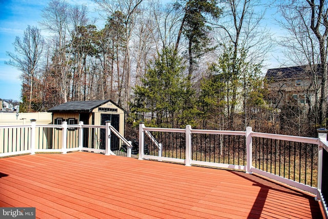 wooden deck featuring an outbuilding, a storage shed, and fence