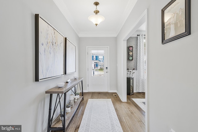 foyer entrance featuring baseboards, crown molding, and light wood finished floors