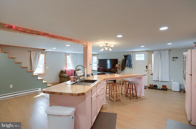 kitchen with a kitchen island with sink, butcher block countertops, a sink, open floor plan, and a kitchen bar