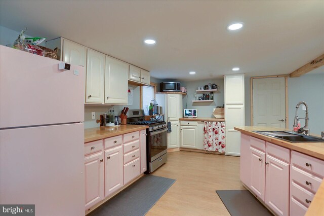 kitchen with recessed lighting, appliances with stainless steel finishes, white cabinetry, a sink, and light wood-type flooring