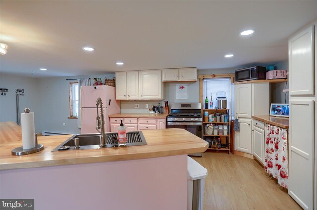 kitchen with stainless steel appliances, recessed lighting, wooden counters, and white cabinets