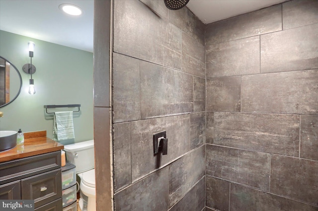 bathroom with a tile shower, vanity, and toilet