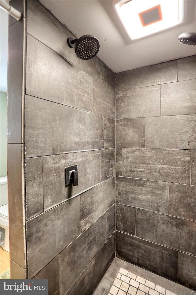 bathroom featuring toilet and a tile shower