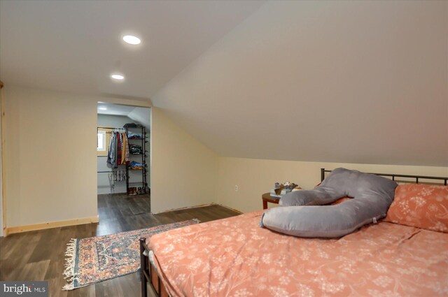 bedroom with baseboards, dark wood-style floors, a spacious closet, vaulted ceiling, and recessed lighting
