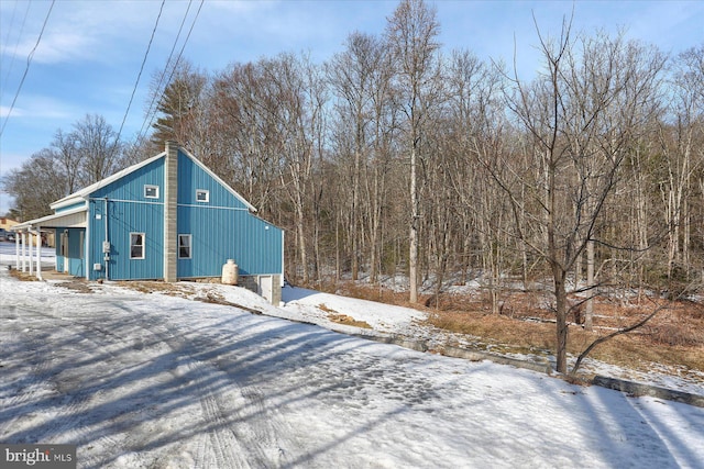 view of snowy exterior with a detached garage
