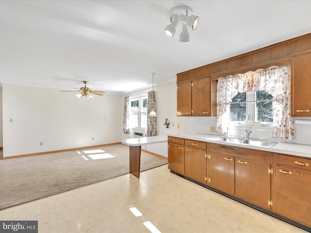 kitchen featuring brown cabinets, a sink, pendant lighting, and light countertops