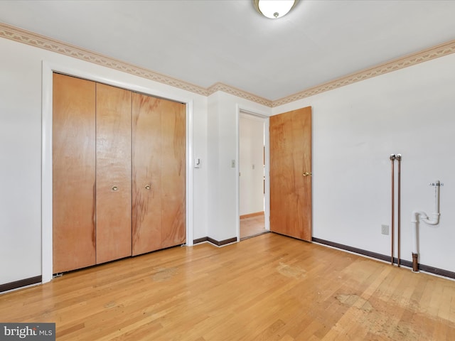 unfurnished bedroom featuring a closet, baseboards, and light wood finished floors