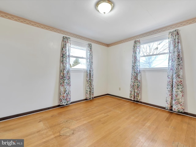 empty room featuring plenty of natural light, baseboards, and wood finished floors