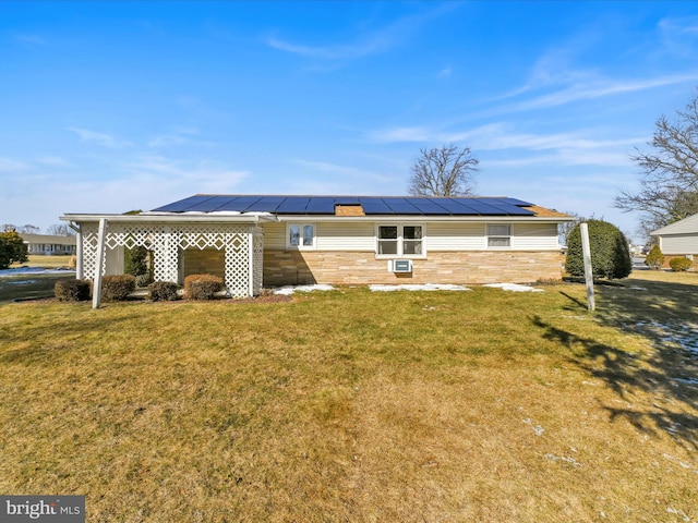 back of property featuring metal roof, solar panels, stone siding, a yard, and a standing seam roof