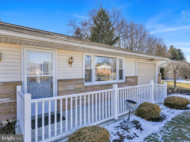 snow covered property entrance with a garage