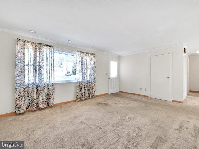 empty room featuring baseboards, light colored carpet, and crown molding