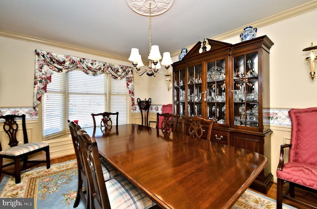 dining room with an inviting chandelier, ornamental molding, and a wainscoted wall