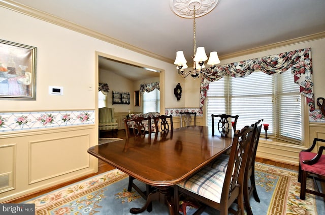 dining room with a chandelier, a wainscoted wall, ornamental molding, and wood finished floors