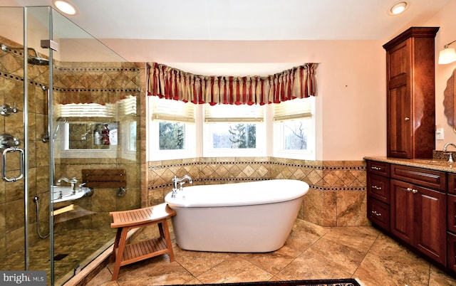 bathroom featuring recessed lighting, vanity, tile walls, a freestanding bath, and a shower stall