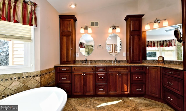 bathroom featuring visible vents, a sink, a freestanding bath, and double vanity