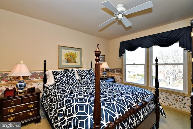 bedroom featuring a wainscoted wall, ceiling fan, wallpapered walls, and light colored carpet