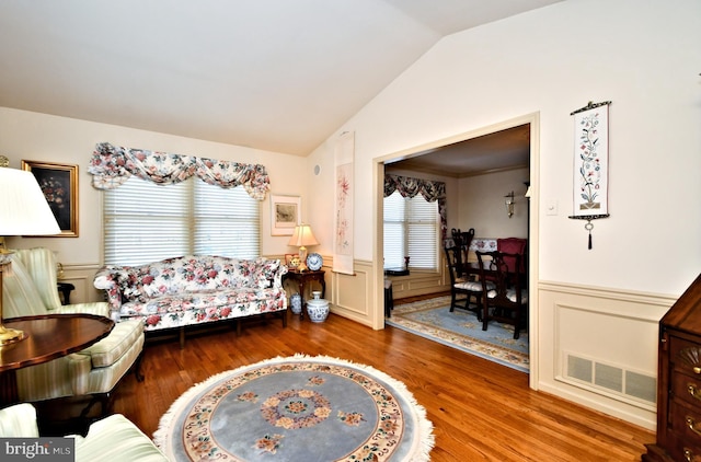 bedroom with lofted ceiling, a wainscoted wall, visible vents, and multiple windows