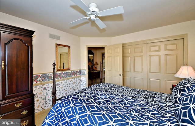 carpeted bedroom featuring ceiling fan, a closet, wainscoting, and visible vents