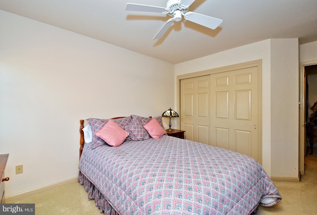 bedroom featuring a ceiling fan, a closet, light carpet, and baseboards