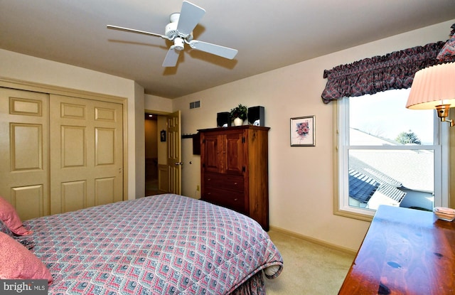 bedroom featuring a closet, light colored carpet, visible vents, a ceiling fan, and baseboards