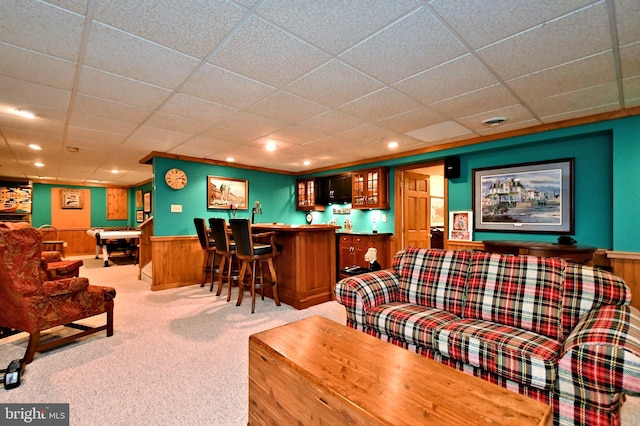 carpeted living area with a dry bar, wood walls, recessed lighting, and wainscoting