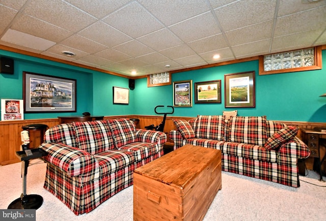 living room with carpet floors, wainscoting, wood walls, and a drop ceiling