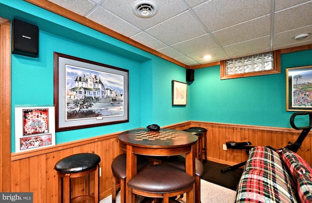 interior space featuring a wainscoted wall, a drop ceiling, visible vents, and wooden walls