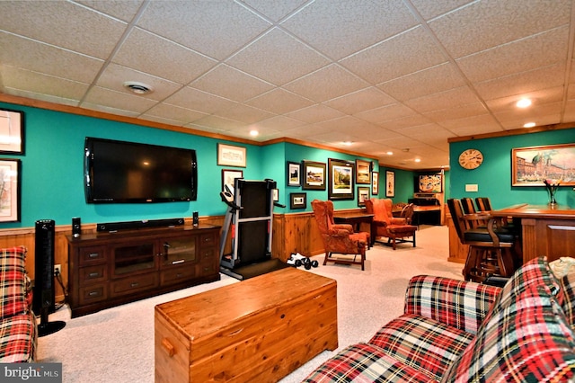 living area featuring a bar, visible vents, light colored carpet, and wainscoting