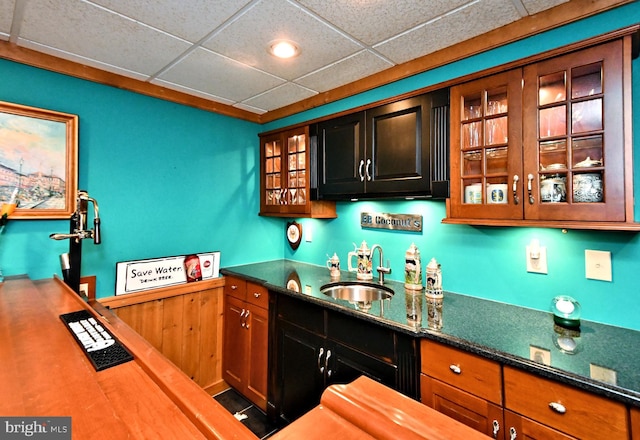 bar featuring a paneled ceiling, indoor wet bar, and a sink